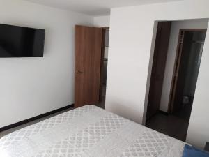 a bedroom with a bed and a flat screen tv at 4 Apartaestudio Cedritos completo in Bogotá