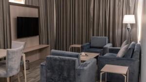 un salon avec des chaises bleues et une télévision dans l'établissement سفن جاردنز وادي وج, à Taif