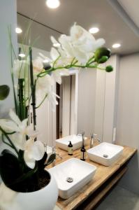 un baño con 2 lavabos y un jarrón con flores blancas en Apartament z Widokiem na Park en Polanica-Zdrój