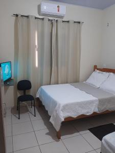 a bedroom with a bed and a chair and a tv at Casa de temporadas Simone/ Rafael in Carolina
