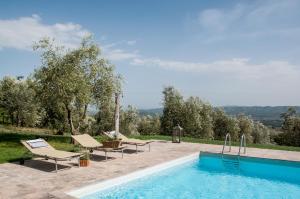 a swimming pool with two lounge chairs next to at Borgo Montefreddo Toscana in San Casciano dei Bagni