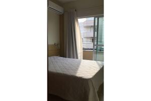 um quarto com uma cama e uma janela em Residencial Gaivotas 05 - 1 Quartos - Completo 30m da praia em Florianópolis