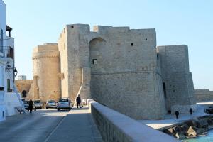 a large castle with cars parked on a street at B&B Al Picchio in Monopoli