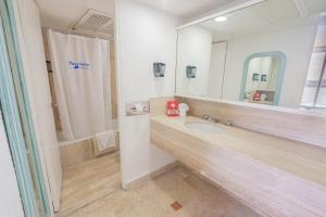 a bathroom with a sink and a large mirror at Playa Suites Acapulco in Acapulco