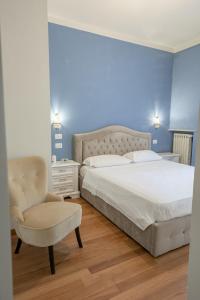 a bedroom with a large bed and a chair at ForliHouse in Forlì