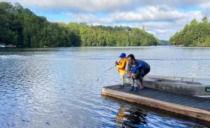 um homem e uma criança numa doca na água em Sunny Point Resort Ltd. em Otter Lake