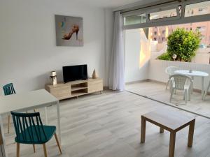 sala de estar con TV, mesa y sillas en Calm, Cosy and Bright apartment renovated in playa del ingles- WiFi free, en Playa del Inglés