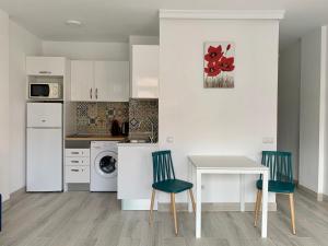 cocina con armarios blancos, mesa y sillas en Calm, Cosy and Bright apartment renovated in playa del ingles- WiFi free, en Playa del Inglés