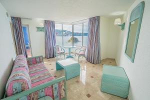 uma sala de estar com um sofá, uma mesa e cadeiras em Playa Suites Acapulco em Acapulco