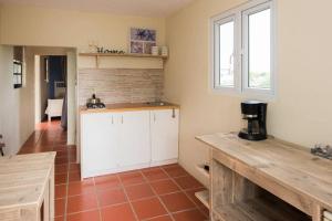 a kitchen with white cabinets and a red tile floor at Smileys Apartment in Willemstad