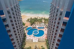 una vista aérea de la piscina y la playa desde dos edificios en Playa Suites Acapulco en Acapulco