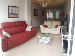 ein Wohnzimmer mit einem roten Sofa und einem Tisch in der Unterkunft gîte Les Coquelicots in Médière