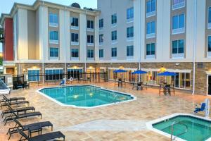 un patio del hotel con piscina, mesas y sillas en Holiday Inn Express Hotel & Suites Mobile Saraland, an IHG Hotel, en Saraland
