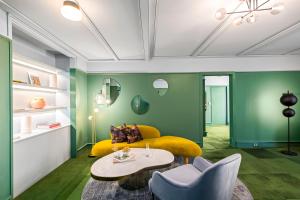 a living room with a yellow couch and green walls at The Central Private Hotel by Naumi Hotels in Queenstown