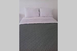 Studio Loft Cozumel في كوزوميل: سرير بملاءات بيضاء وبطانية رمادية
