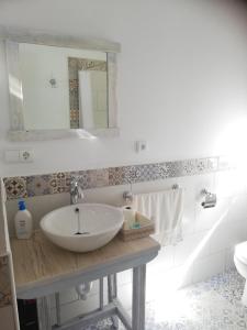 Baño blanco con lavabo y espejo en Hostal el lugar de la Mancha, en Argamasilla de Alba