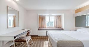 a bedroom with a bed and a desk and windows at SureStay Hotel by Best Western Christiansburg Blacksburg in Christiansburg