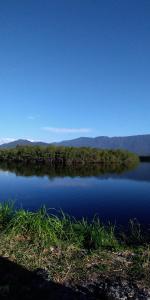 uma vista para um lago com árvores e água azul em Cantinho da Lu em apt inteiro 800 mt da praia em Bertioga