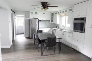 a kitchen with white cabinets and a table and chairs at Entire waterfront cottage in carrying place in Carrying Place