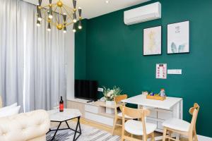 a living room with a green wall and a table and chairs at Helen Fin Inn & Apartment in Phnom Penh