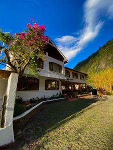 un edificio con un árbol con flores rosas. en Hotel Volcano Baños, en Baños