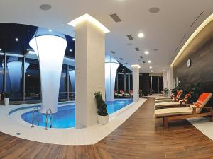 a hotel lobby with a swimming pool and chairs at Vysotsky Hotel in Yekaterinburg