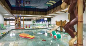 een groot binnenzwembad met een speeltuin met glijbanen bij CGH Résidences & Spas Kalinda in Tignes