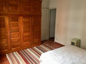 a bedroom with a bed and a large wooden cabinet at Apartamento PRAIA do TOMBO - Guarujá in Guarujá