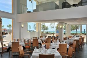 a restaurant with white tables and chairs and windows at Hotel Hispania in Playa de Palma