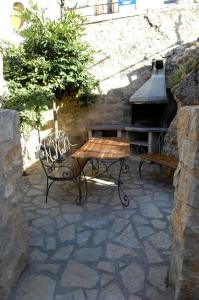 a stone patio with a bench and a grill at Casa Juan in Orihuela del Tremedal