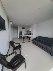 Una sala de estar con un sofá y sillas y una mesa. en Hermoso apartamento a 300 m Playa Bello Horizonte Pozos colorados, en Santa Marta