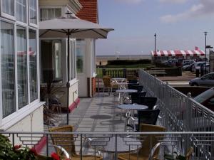 eine Terrasse mit Tischen, Stühlen und einem Sonnenschirm in der Unterkunft Marine Lodge in Great Yarmouth