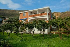 a house on a hill with trees in the foreground at Apartments Katarina Garden in Petrovac na Moru