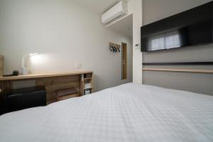 1 dormitorio con cama blanca y escritorio en R&B Hotel Nagoya Shinkansenguchi, en Nagoya