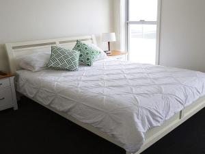 1 cama blanca con almohadas en el dormitorio en Jones Beach House, en Kiama Downs