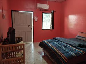1 dormitorio con paredes rojas, 1 cama y puerta en Home hug villa, en Ban Bang Rin (1)