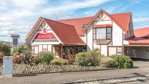 a building with a red roof on a street at Burwood Motel in Whanganui