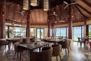 un restaurante con mesas, sillas y ventanas en Pavilion Samui Villas and Resort - SHA Extra Plus, en Lamai