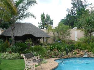 a garden with a bench next to a swimming pool at Littlefield Luxury Suite in Johannesburg