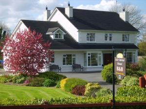 een wit huis met een bord ervoor bij Lake Avenue House in Ballyconnell