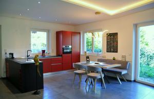 cocina con armarios rojos, mesa y sillas en Ruhige Ferienwohnung mit Garten und Garage in Privatvilla, en Marlengo