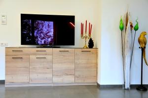 uma televisão em cima de uma cómoda de madeira num quarto em Ruhige Ferienwohnung mit Garten und Garage in Privatvilla em Marlengo