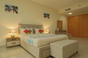 a bedroom with a large bed and a stool at OYO 592 Home 308 sillicon oasis in Dubai
