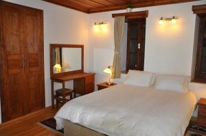 a bedroom with a large white bed and a mirror at Ionia House in Selcuk