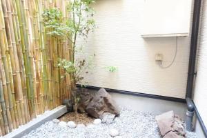 a garden with a bamboo fence and a tree at Fukenouchi House in Kyoto