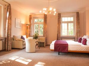 a bedroom with a bed and a couch and windows at Aparthotel Villa Freisleben in Dresden