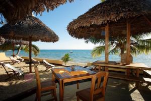 un tavolo, sedie e ombrelloni su una spiaggia di Sambatra Bed and Breakfast a Ambaro