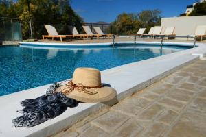 a straw hat sitting on a ledge next to a swimming pool at MASSOURI BEACH HOTEL in Masouri