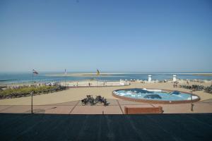 uma vista para uma praia com uma piscina e o oceano em Strandhotel Ostfriesenhof em Borkum