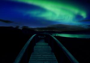 a boardwalk under the aurora borealis at night at Hotel Glymur in Hvalfjarðarsveit